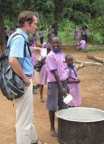 Christopher serves up some posho for lunch to visitor, Dave Kay, at Hope for Youth School